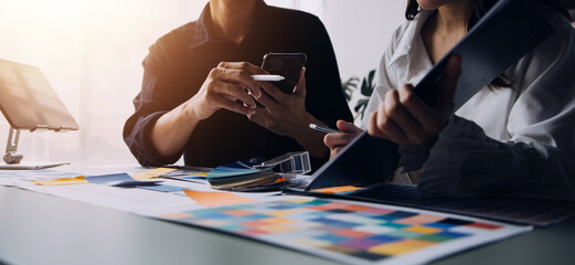 Close up ux developer and ui designer brainstorming about mobile app interface wireframe design on table with customer breif and color code at modern office.Creative digital development agency