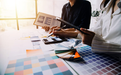 Close up ux developer and ui designer brainstorming about mobile app interface wireframe design on table with customer breif and color code at modern office.Creative digital development agency