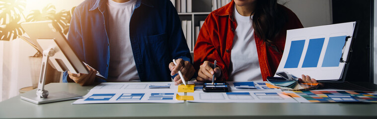 Close up ux developer and ui designer brainstorming about mobile app interface wireframe design on table with customer breif and color code at modern office.Creative digital development agency
