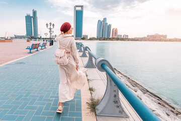 Wall Mural - A young Indian woman proudly wears a turban as she strolls along the Abu Dhabi embankment, celebrating her cultural heritage and identity.