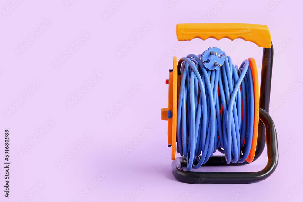 Extension electric cable reel on lilac background