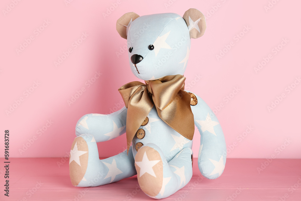 Toy bear on table near pink wall