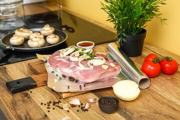 Wall Mural - Aluminium foil roll with raw piece of meat, spices and vegetables on wooden table in kitchen