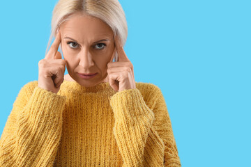 Wall Mural - Thoughtful mature woman on blue background, closeup