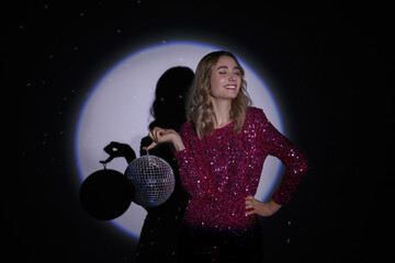 Beautiful woman with disco ball in spotlight on dark background
