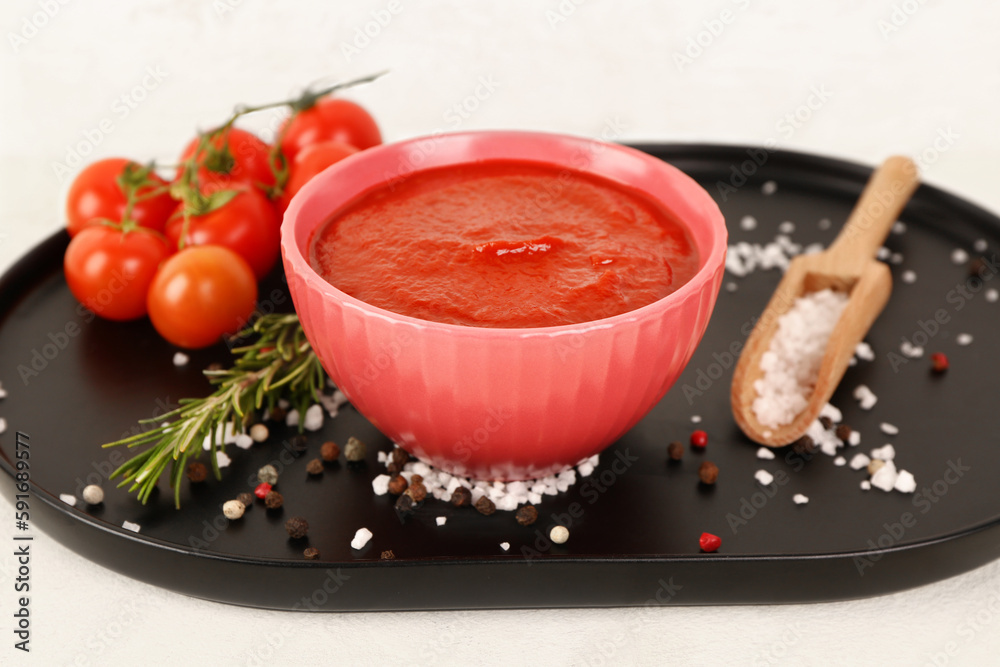 Bowl with tasty tomato paste on light background
