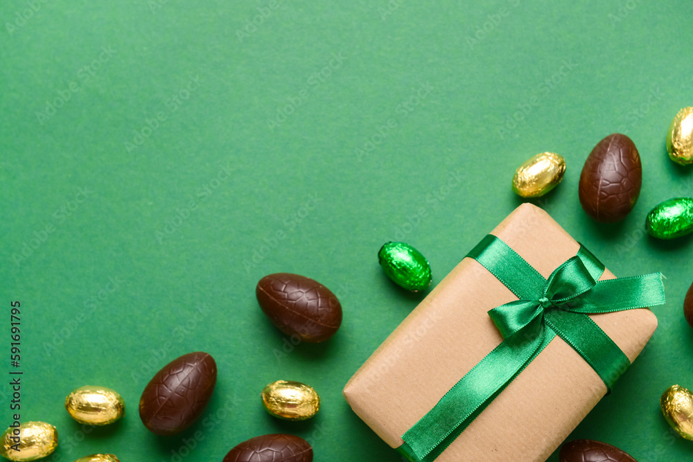 Chocolate Easter eggs and gift box on green background