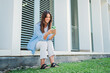 © Jose Calsina - joyful caucasian woman smiling and browsing on internet with a mobile phone, texting emails, connecting people sitting outside. Young teenage female student using a cellphone app at university campus