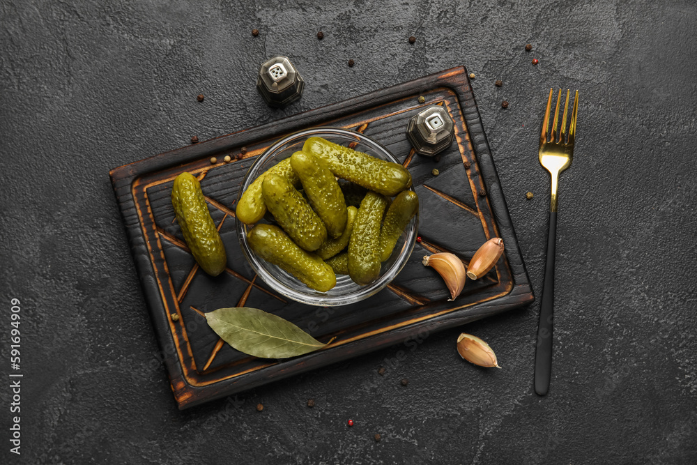 Bowl with tasty fermented cucumbers on dark grunge background