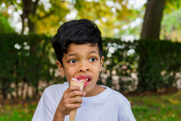 Close-up of a young boy eating ice-cream outdoors in a park.