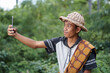 © Berlian - Rural man sitting on tree trunk holding smartphone in the forest