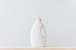 Washing gel liquid laundry detergent or fabric softener on a wooden table against a light white background with copy space.