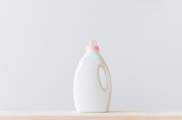 Washing gel liquid laundry detergent or fabric softener on a wooden table against a light white background with copy space.