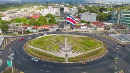 Wall Mural - SAN JOSE, COSTA RICA - FEBRUARY 28, 2023 - Rotonda de la Bandera (The Flag) roundabout in San Pedro. Aerial drone view, backward movement, daylight.
