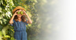 © _KUBE_ - Gardening web banner. A cute little girl in a straw hat holds passion fruit near her eyes. Mock up with space. The concept of organic farming and harvesting