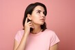 © Nataly - Portrait of a young woman in pink t-shirt looking up thinking, isolated on pink background. Ai generative.