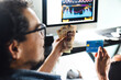 © Marcos - Financial Man holding credit card for shopping online with desktop computer at background in Mexico Latin America