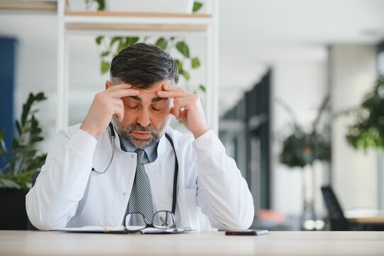 Senior caucasian man wearing doctor uniform and stethoscope at the clinic rubbing eyes for fatigue and headache, sleepy and tired expression. vision problem