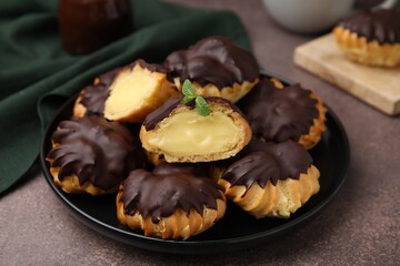 Delicious profiteroles with chocolate spread and cream on textured table, closeup