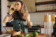 © Jacob Lund - Vegan woman drinking green juice in her kitchen