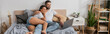 © LIGHTFIELD STUDIOS - cheerful african american woman with bearded boyfriend watching film on laptop in modern bedroom at home, banner.