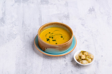 Sticker - Top view of a pumpkin soup in a bowl with bread crumbs on the side on a white table