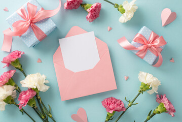 Wall Mural - Mother's Day joy concept. Top view flat lay photo of open blank envelope beautiful present boxes with pink ribbons, carnation flowers, and pink paper hearts on pastel blue background
