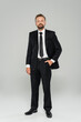 © LIGHTFIELD STUDIOS - full length of bearded man in formal wear standing with hand in pocket on grey.
