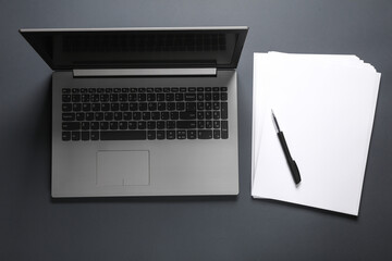 laptop and white a4 paper with a pen on a dark background. business concept. flat lay