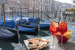 Spritz for two with snacks in Venice with the backdrop of the Canale Grande and moored gondolas.
