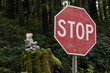 © Designpics - Close-up of a stop sign beside a forested area with moss and a cairn in the background in the community of Bamfield on Vancouver Island; Bamfield, British Columbia, Canada