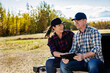© Designpics - A husband and wife using a portable wireless device to manage and monitor their Canola harvest while sitting on the tailgate of their truck; Alcomdale, Alberta, Canada