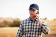 © Designpics - A man talking on a smart phone while monitoring and completing fall canola harvest; Alcomdale, Alberta, Canada