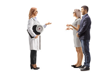 Wall Mural - Full length profile shot of a  female doctor holding a weight scale and talking to a young couple