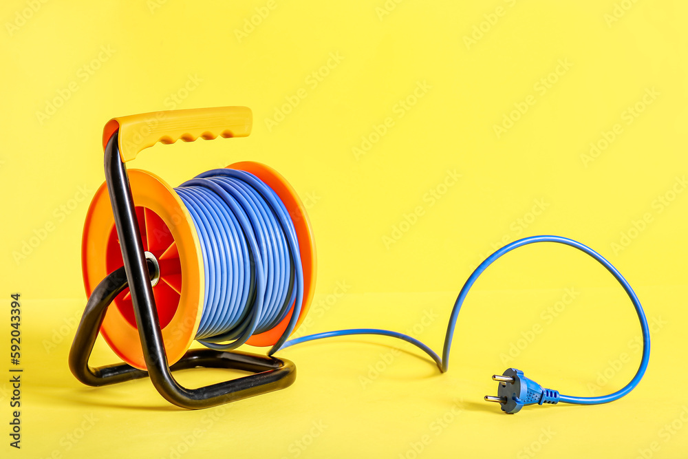 Extension electric cable reel on yellow background