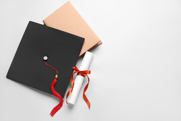 Diploma with red ribbon, graduation hat and book on white background