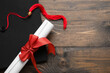 © Pixel-Shot - Diploma with red ribbon and graduation hat on wooden table