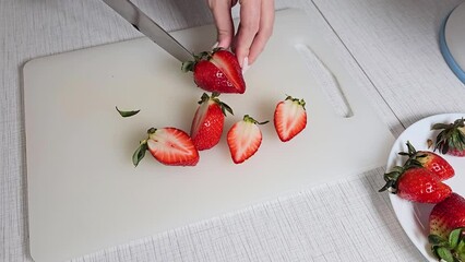 Wall Mural - Women's hands are slicing ripe red strawberries 