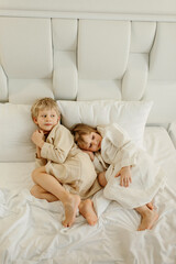 Wall Mural - Brother and sister lying on the bed in bathrobes after a shower