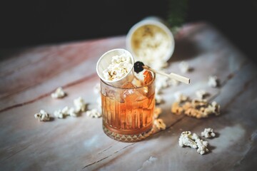 Angled Side View of Old Fashioned with Popcorn Garnish: Unique Twist, Whiskey Delight, Amber Color, Icy Refreshment, Creative Mixology, Playful Touch, Sophisticated Drink