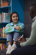 © Seventyfour - Vertical portrait of stressed teenage girl talking to mental health therapist in college library
