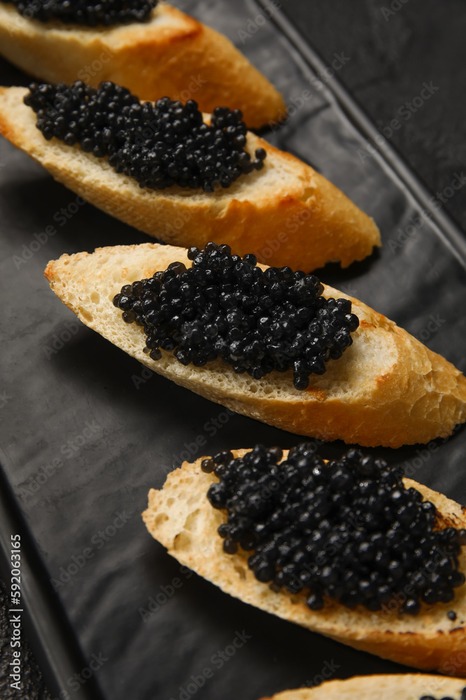 Tasty bruschettas with black caviar on dark background