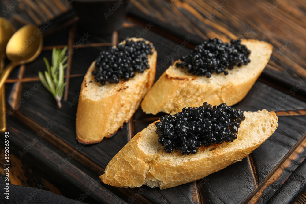 Tasty bruschettas with black caviar on wooden background