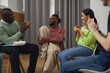 © Seventyfour - Diverse young people in support group circle applauding to smiling black man sharing success story