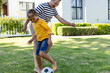 © Wavebreak Media - Cheerful caucasian grandfather and grandson playing soccer on grassy field in yard, copy space