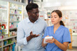 © JackF - Young female pharmacist advises a man visitor a good skin care remedy, standing in the sales hall of a pharmacy