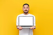 asian man in white t-shirt shows blank laptop screen on yellow isolated background