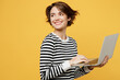© ViDi Studio - Young smiling happy fun IT woman wears casual striped black and white shirt hold use work on laptop pc computer look aside on area isolated on plain yellow color background studio. Lifestyle concept.