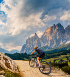 Fototapeta Las - Woman ride electric mountain bikes in the Dolomites in Italy. Mountain biking adventure on beautiful mountain trails.