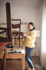 Wall Mural - Woman working in a small home workshop for furniture repairing and restoration.